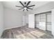 Bright bedroom featuring wood-look floors, a ceiling fan, and a large closet with built-in shelving at 14115 Nw 141St Ave, Williston, FL 32696
