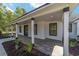 Charming covered porch featuring elegant white columns, gray wood-look flooring, and landscaped surroundings at 14115 Nw 141St Ave, Williston, FL 32696
