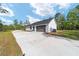Spacious driveway leading to a modern home with a unique garage door and well-maintained landscaping at 14115 Nw 141St Ave, Williston, FL 32696
