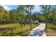 A well-maintained single-story home with a long, inviting driveway and beautiful landscaping, nestled among tall trees at 14115 Nw 141St Ave, Williston, FL 32696