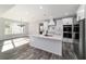 Open concept kitchen with a large island, white cabinets, wood look tile flooring, and modern lighting fixtures at 14115 Nw 141St Ave, Williston, FL 32696