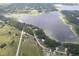 An aerial shot of a lake with surrounding residences near tree-lined streets and open fields at 22764 Sw Sea Cliff Ave, Dunnellon, FL 34431