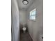 Clean and compact powder room featuring new toilet, gray floors, and a bright window at 22764 Sw Sea Cliff Ave, Dunnellon, FL 34431