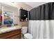 Bathroom featuring granite counters, dark wood cabinets, and shower with decorative white and black curtain at 4243 Se 131St Ln, Belleview, FL 34420