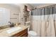 Bathroom featuring granite counters, dark wood cabinets, and shower with decorative white and gray curtain at 4243 Se 131St Ln, Belleview, FL 34420