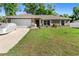 Single-story home featuring an attached garage, well-kept lawn, and a car covered with a silver protector at 4243 Se 131St Ln, Belleview, FL 34420