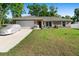 Charming single story home with a well-maintained lawn and a covered car in the driveway at 4243 Se 131St Ln, Belleview, FL 34420