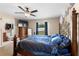 Comfortable primary bedroom with a ceiling fan, carpet floors, a window view to the backyard, and an en-suite bathroom at 4243 Se 131St Ln, Belleview, FL 34420