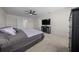 Bright bedroom showcasing neutral carpet, ceiling fan, and a sleek entertainment center below a wall-mounted television at 4806 Sw 86Th Ln, Ocala, FL 34476