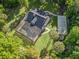 Aerial view of estate home with pool, screened enclosure, surrounding lush landscaping, and a basketball court at 6577 Nw 193Rd St, Micanopy, FL 32667