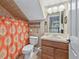 Compact bathroom featuring a wood vanity, floral shower curtain, and earth-toned tiles at 6577 Nw 193Rd St, Micanopy, FL 32667