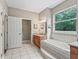 Bright bathroom featuring a large soaking tub, neutral-toned tile, and a window with nature views at 6577 Nw 193Rd St, Micanopy, FL 32667