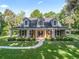 Charming home with a large front porch, rocking chairs, and lush landscaping at 6577 Nw 193Rd St, Micanopy, FL 32667