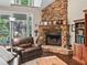 A cozy living room with a stone fireplace, hardwood floors, and natural light from the windows at 6577 Nw 193Rd St, Micanopy, FL 32667