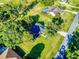 An aerial view of a home with a well manicured lawn, mature trees, and nearby residential street at 7787 Nw 56Th Pl, Ocala, FL 34482