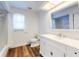 Bright bathroom featuring a white vanity with marble countertop and wood-look flooring at 7787 Nw 56Th Pl, Ocala, FL 34482
