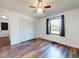 Bedroom features laminate flooring, ceiling fan, closet, and window with black-out curtains at 7787 Nw 56Th Pl, Ocala, FL 34482