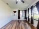 Sunroom boasts wood floors, a ceiling fan, and large windows with dark curtains at 7787 Nw 56Th Pl, Ocala, FL 34482