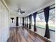 Sunroom boasts wood floors, a ceiling fan, and large windows with dark curtains at 7787 Nw 56Th Pl, Ocala, FL 34482