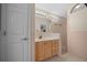 Bright bathroom featuring a wooden vanity, large mirror with lighting, and a tiled shower at 882 Tanglewood Pl, The Villages, FL 32162