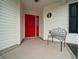 Cozy covered front porch featuring a vibrant red door and an ornamental bench at 882 Tanglewood Pl, The Villages, FL 32162