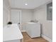 Bright laundry room with white washer and dryer, white countertop and shelving, and wood look floors at 113 Weeping Elm Ln, Longwood, FL 32779