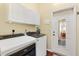 Efficient laundry room with modern washer and dryer, cabinets, and an exterior door at 17536 Se 119Th Cir, Summerfield, FL 34491