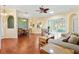 Inviting living room with hardwood floors, a ceiling fan, and seamless access to dining and sunroom areas at 17536 Se 119Th Cir, Summerfield, FL 34491