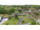 Aerial view of a home with a circular driveway, green roof, surrounded by mature trees and lush lawns at 1866 Ne 39Th Ct, Ocala, FL 34470
