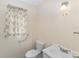 Bathroom with toilet, white sink, and window with floral curtain at 1866 Ne 39Th Ct, Ocala, FL 34470