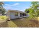 A view of the backyard and screen porch of a blue home, surrounded by lush trees at 2199 Se 175Th Ter, Silver Springs, FL 34488