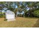 Blue storage shed with roll-up door on grassy lot beneath mature trees at 2199 Se 175Th Ter, Silver Springs, FL 34488