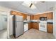Functional kitchen with wood cabinets, tile floors, stainless steel refrigerator and white appliances at 2300 Ne 49Th St, Ocala, FL 34479