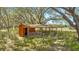 Rustic red barn with an open-air design and wooden fencing, nestled amongst large trees and foliage at 3360 Se 183Rd Avenue Rd, Ocklawaha, FL 32179