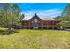 Stunning log cabin home with a metal roof and a large front porch, set against a backdrop of lush greenery at 3360 Se 183Rd Avenue Rd, Ocklawaha, FL 32179