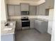 Modern kitchen featuring stainless steel appliances, gray cabinets, and granite countertops at 5077 Stokes Way, Wildwood, FL 34785