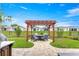 Landscaped backyard with pergola-covered seating area perfect for outdoor dining and entertaining at 5220 Sunshine Dr, Wildwood, FL 34785
