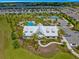 An aerial view of a community clubhouse featuring lush landscaping, a pool, and ample parking at 5220 Sunshine Dr, Wildwood, FL 34785