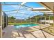 A screened-in pool with clear blue water, patio, lounge chairs, and surrounding greenery under a bright blue sky at 5580 Se 21St Ln, Ocala, FL 34480