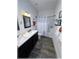 Modern bathroom showcasing double sinks, dark cabinets, subway tile, and wood-look tile floors at 6365 Se 12Th Ln, Ocala, FL 34472