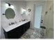 Modern bathroom featuring dual sinks, dark cabinetry, decorative tile flooring, and a glass-enclosed shower at 6365 Se 12Th Ln, Ocala, FL 34472