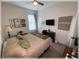 Bright bedroom with a ceiling fan, bed with quilt, television, and artwork on the wall at 6365 Se 12Th Ln, Ocala, FL 34472