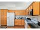Kitchen with wood cabinets, black granite counters, and white appliances at 712 Harper Pl, Lady Lake, FL 32159