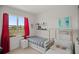 Bright bedroom with a twin bed, cushioned seating, and a view of a green field out the large window at 7687 Sw 63Rd Place Rd, Ocala, FL 34474