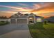 Inviting home exterior featuring a well-manicured lawn and a two-car garage against a breathtaking sunset sky at 9074 Se 48Th Court Rd, Ocala, FL 34480