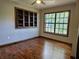 Cozy bedroom featuring gleaming hardwood floors, a built-in bookshelf, and a large window offering serene views at 1047 Ne 19Th St, Ocala, FL 34470