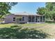 View of the screened-in lanai in the backyard with a well-kept lawn and mature trees at 1213 Meadowbend Dr, Leesburg, FL 34748