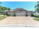Single-story home boasts a three-car garage, stamped concrete driveway, and attractive landscaping at 1213 Meadowbend Dr, Leesburg, FL 34748