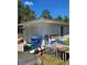 View of the one-car garage with an off-white door and driveway, next to miscellaneous yard items at 1441 Admiral Nimitz Ave, Daytona Beach, FL 32124