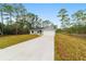 Charming single-story home featuring a gray exterior, attached garage, and long concrete driveway surrounded by beautiful trees at 24354 Nw Water Oak Ave, Dunnellon, FL 34431